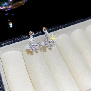 Elegant silver bow earrings with zircon stones displayed on a cream jewelry box