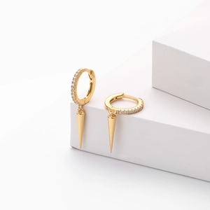Detailed view of gold cone drop earrings with shimmering zircon pavé on white stand