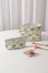 Detail view of white cotton linen makeup bag set with green floral embroidery accents