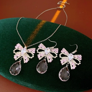 Detail of luxury bowknot jewelry set with pink stones and purple teardrop crystals