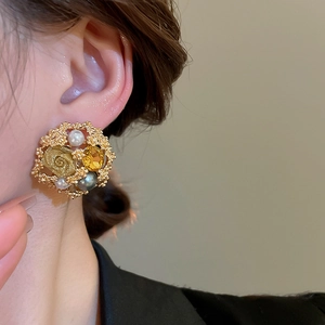 Detail of vintage flower stud earring with pearls and yellow gemstone on model