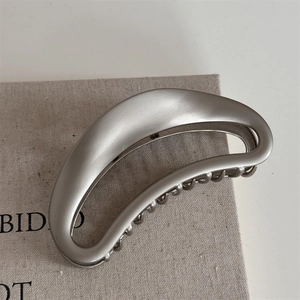 Macro shot of matte silver alloy crescent hair claw clip with hollow metal structure