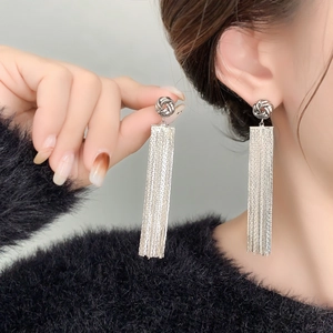 Detail shot of long silver tassel earrings with a knotted design worn by a model