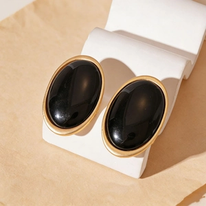 Close-up of vintage oval geometric earrings with gold metal frame and black resin center