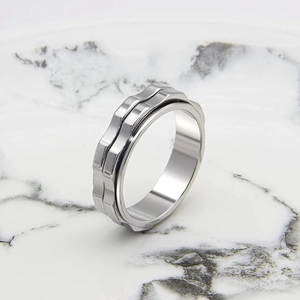 Detail of silver spinning gear ring on marble background showing rotating steel mechanism
