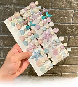 Detail of macaron hair clips with shell, mermaid tail, and star shapes on display cards