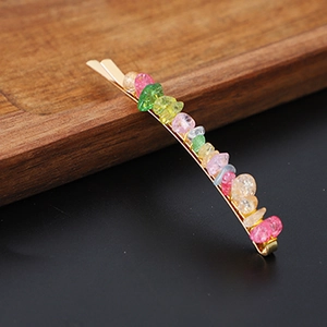 Detail of a gold metal hair clip adorned with colorful natural crystal gravel stones