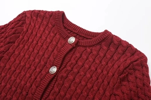 Close-up of wine red cable-knit cardigan featuring vintage silver embossed metal buttons