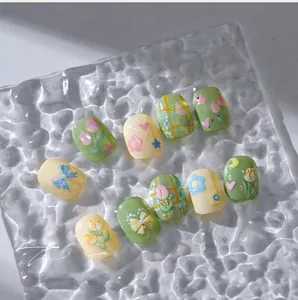 Detail of 3D tulip and bow nail stickers with pearls on green and yellow nails