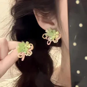 Detail of multi-layered flower earrings with matte green petals and macaron color frames