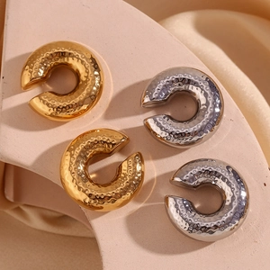 Macro detail of textured hammered finish on 18K gold and silver plated C-shaped earrings