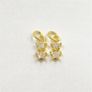 Detailed macro view of gold-plated double star pendants with clear zircon stones