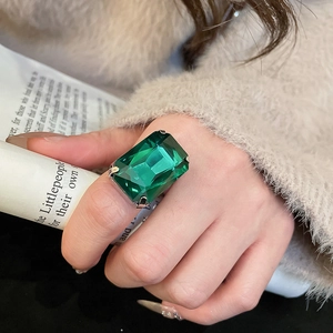 Detail shot of a large square green gemstone ring on finger with silver plated band