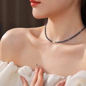 Detailed shot of titanium steel necklace with dark beads and a white freshwater pearl accent
