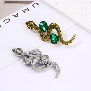 Detail of snake brooch featuring green gemstones on gold and silver metal backing