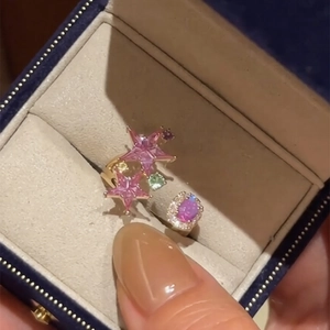 Adjustable gold star ring with pink zircon and purple gemstones displayed in a jewelry box