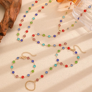 Colorful gemstone jewelry set with necklace and bracelets on natural sand background