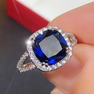 Close-up of a silver ring with a large square royal blue gemstone and pavé diamonds