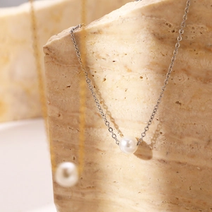 Minimalist stainless steel necklace featuring a round white pearl pendant in silver and gold