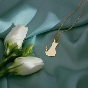 Vue macro d'un pendentif chat minimaliste en or sur un fond élégant en tissu de soie