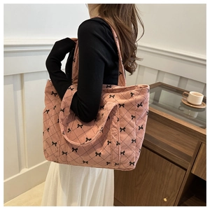 Détail d'un cabas en velours côtelé rose avec motifs de nœuds noirs et losanges