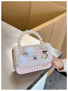 Close-up of pink houndstooth bag with pearl handle, lace trim, and bow charms