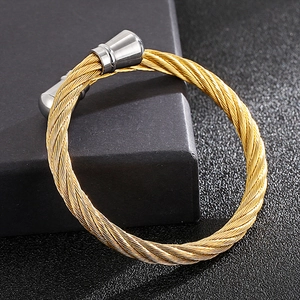 Close-up of gold twisted wire bangle with silver metal end caps on a black surface