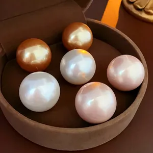 Elegant vintage round pearl stud earrings in gold, white, and pink on brown velvet tray