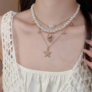 Detailed view of triple-layered ocean theme necklace with starfish and baroque pearl on neck