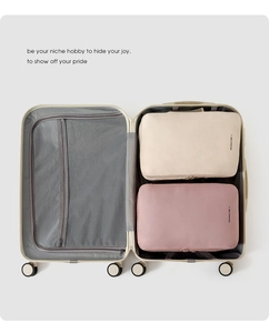 Vue détaillée des sacs de voyage beige et rose en taille L dans une valise ouverte