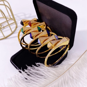 Macro detail of gold-tone bangles with multi-color stones in a black velvet jewelry box