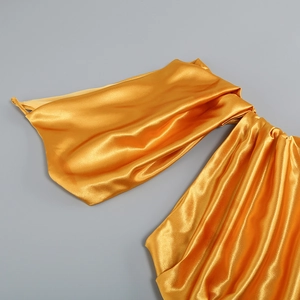 Détail d'une robe en satin doré élégante avec texture plissée et drapé luxueux en tissu
