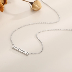 Macro detail of 18k gold plated mama pendant on a minimalist stainless steel chain