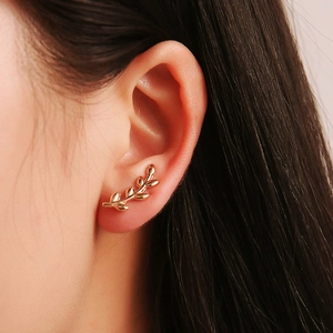 Macro shot of gold leaf-shaped ear crawler earring on model side profile view