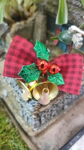 Detail of Christmas plaid bow with gold bells and red berries on miniature stone decor