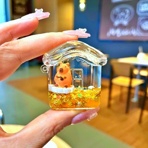 Detail of Capybara-themed liquid sand earphone case with golden flowing glitters