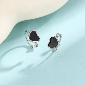 Minimalist silver heart ear cuffs with black enamel inlay on light blue background