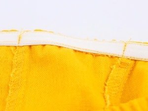 Detailed macro view of the elastic waistband and stitching on the yellow maxi dress