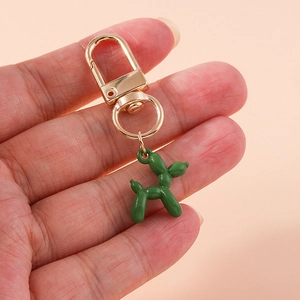 Detail of green balloon dog keychain with golden metal clasp held in hand