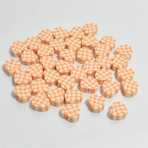 Macro shot of 10mm orange and white checkered heart clay beads for DIY jewelry making