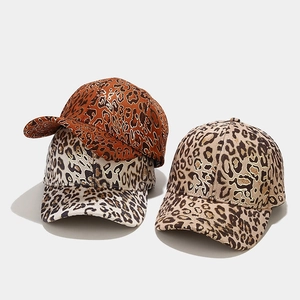 Dettaglio di cappellini da baseball leopardati con accenti dorati in tre colori diversi