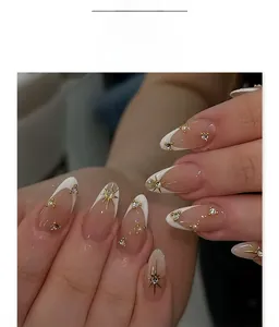 Detail of French white tip press-on nails with golden stars and pearl accents