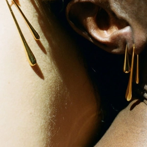 Close-up of elegant gold teardrop earrings worn by a model with artistic lighting
