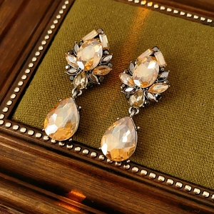 Macro detail of vintage teardrop earrings with champagne gemstones on green velvet box