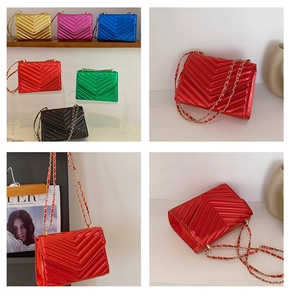 Macro detail of glossy V-quilted faux leather crossbody bag with metal chain strap