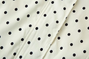 Close-up of polka dot print fabric with neat stitching on a long sleeve jacket