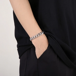 Close-up of a chunky silver stainless steel Cuban link chain bracelet on a male wrist