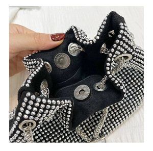 Detail of silver magnetic buckle and chain strap on black rhinestone bucket bag