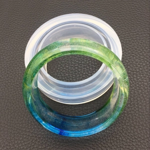 Dettaglio dello stampo in silicone DIY con bracciale in resina sfumata su pelle nera