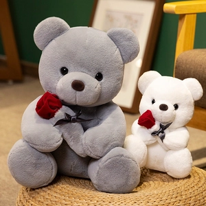 Ositos de peluche grises y crema con rosas rojas sobre una alfombra tejida decorativa